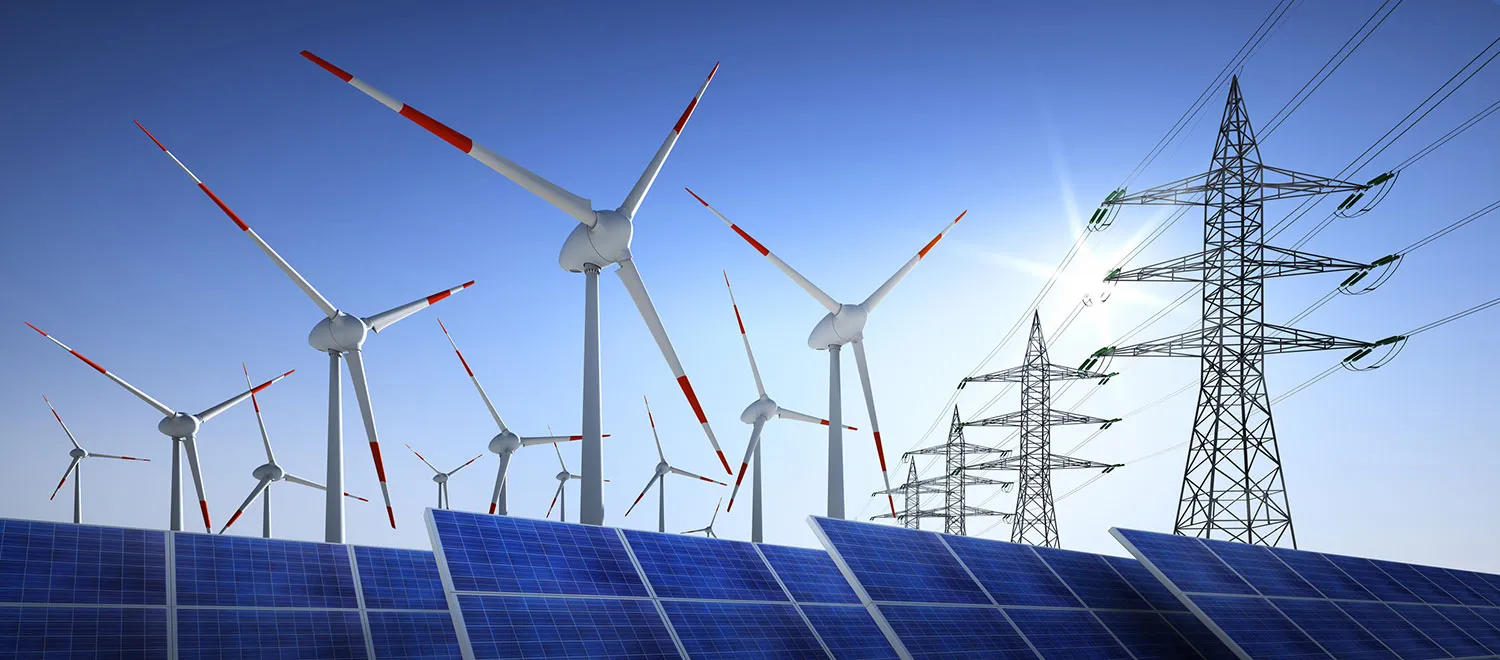 Windräder, Solarmodule und Strommasten unter blauem Himmel